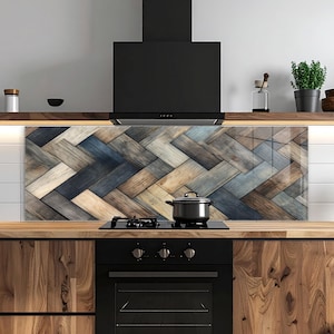 May include: A kitchen backsplash featuring a herringbone pattern in shades of brown, blue, and grey. The backsplash is above a black hob and oven. A black extractor fan is above the backsplash. A stainless steel saucepan sits on the hob.