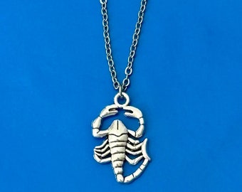 Puede incluir: Un collar de cadena de plata con un colgante de escorpión de plata. El escorpión es detallado y tiene un diseño realista.