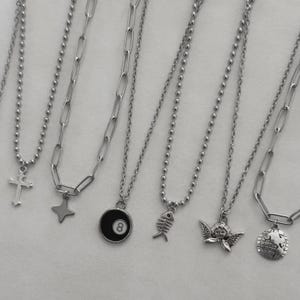 Puede incluir: Un juego de tres tazas de cerámica con un acabado mate moteado. Las tazas son de color crema, gris claro y gris oscuro. Cada taza tiene un diseño simple y minimalista y un asa redondeada.