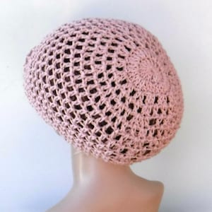 May include: A light pink crocheted hat with an open weave design. The hat is round and fits snugly on the head. The hat is made of a soft, lightweight yarn, perfect for warm weather.