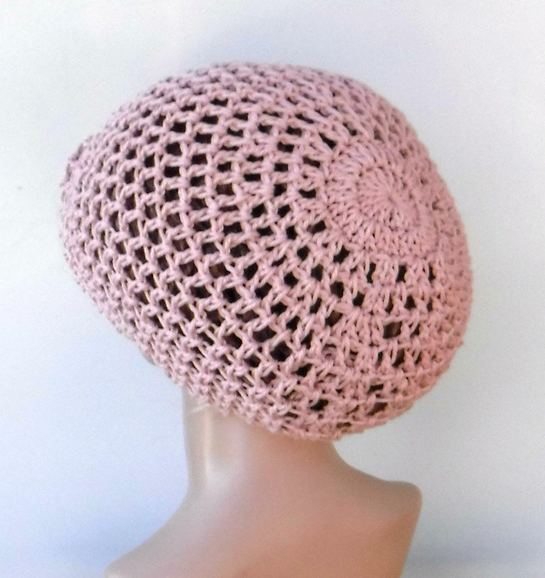 May include: A light pink crocheted hat with an open weave design. The hat is round and fits snugly on the head. The hat is made of a soft, lightweight yarn, perfect for warm weather.