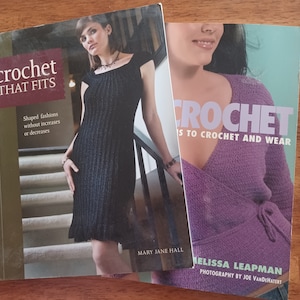 May include: Two crochet books with models wearing crocheted garments. The book on the left is titled "Crochet That Fits" and the book on the right is titled "Crochet Is To Crochet And Wear".