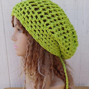 May include: A lime green crochet beanie with a long tie. The beanie is made with a loose, open stitch.