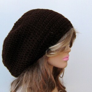 May include: A brown crocheted beanie hat with a slouchy fit. The hat is made with a simple stitch pattern and has a relaxed, casual look.