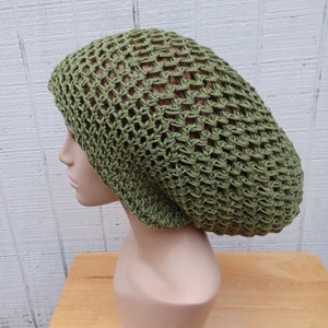 May include: A green crocheted beanie with a loose, slouchy fit. The beanie is made of a lightweight, breathable material and has a mesh-like texture.