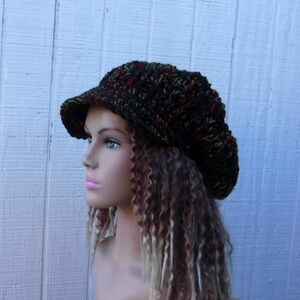 May include: A brown, green, and orange crocheted beanie with a brim. The beanie is slouchy and has a casual style.