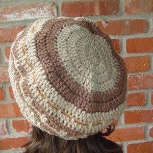 May include: A crocheted hat with a brown and beige striped pattern. The hat is made with a thick yarn and has a simple, classic design.