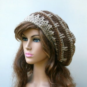 May include: A brown and beige crocheted beanie hat with a slouchy fit. The hat has a textured pattern and is made with soft yarn.