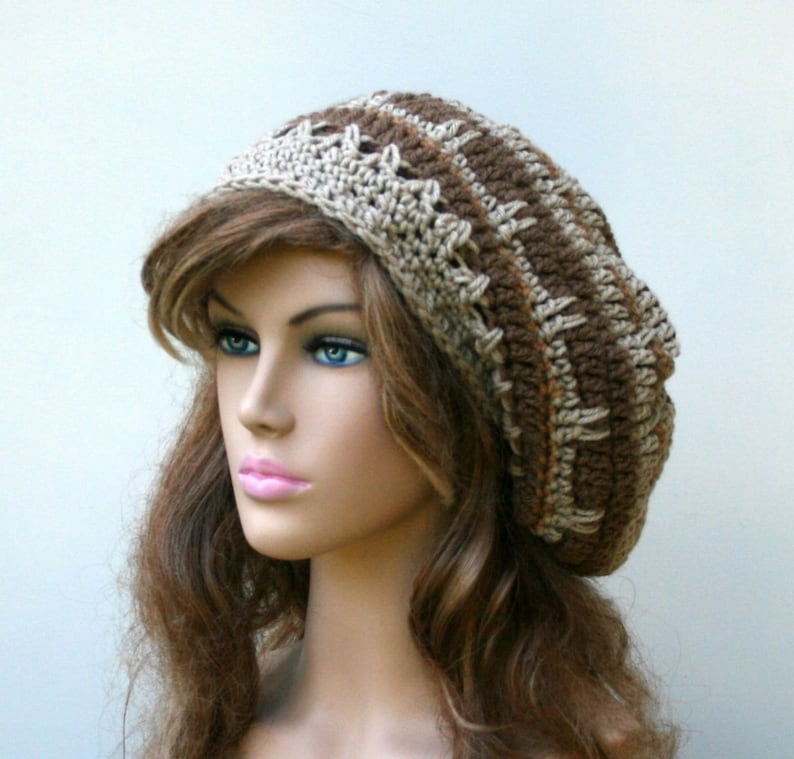 May include: A brown and beige crocheted beanie hat with a slouchy fit. The hat has a textured pattern and is made with soft yarn.
