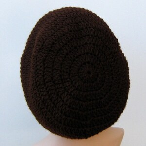 May include: A brown crocheted beanie hat. The hat is made with a simple stitch pattern and has a rounded crown.
