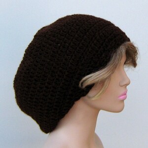 May include: A brown crocheted beanie hat with a slouchy fit. The hat is made with a simple stitch pattern and has a relaxed, casual look.