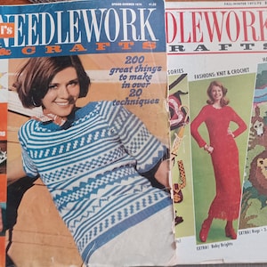 May include: Two vintage issues of "Needlework & Crafts" magazine. The Spring-Summer 1974 issue features a woman wearing a blue and white patterned sweater. The Fall-Winter 1973-75 issue showcases a woman in a red dress. Both covers display the magazine's title.