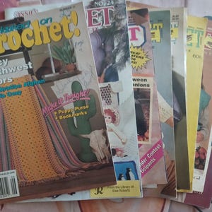 May include: A stack of vintage crochet magazines. The top magazine features the title "Hooked on Crochet!" with the subtitle "Saucy Southwest Colors." Other magazines are visible, with titles like "ET" and "Great Patterns." The magazines are in various colors, including yellow, pink, and green.
