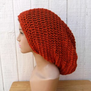 May include: A bright orange crochet beanie with a loose, open weave.