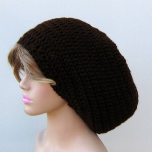 May include: A brown crocheted beanie hat. The hat is large and loose fitting, with a slouchy style.