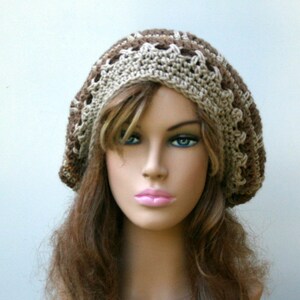 May include: A brown and beige crocheted beanie with a decorative stitch pattern. The beanie is worn on a mannequin with long brown hair.