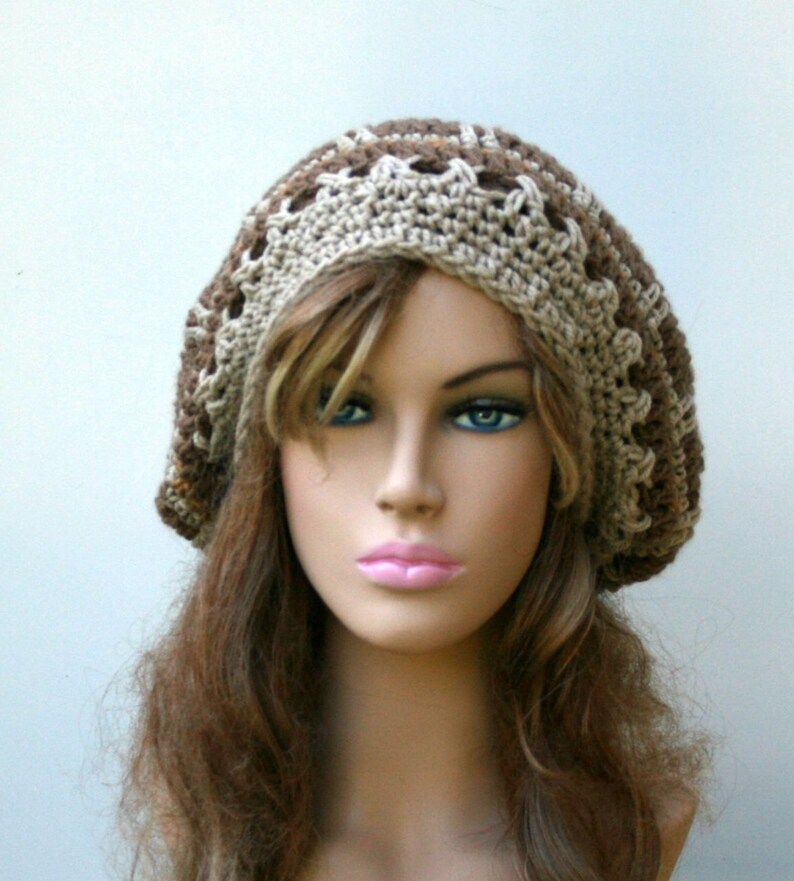 May include: A brown and beige crocheted beanie with a decorative stitch pattern. The beanie is worn on a mannequin with long brown hair.