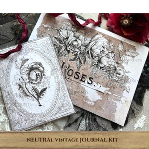 May include: A journal kit featuring two rectangular paper sheets with black and white botanical illustrations of roses. One sheet displays a single rose in an oval frame, while the other shows a rose cluster and the text ROSES. The paper has a brown, aged texture.