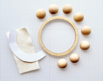 May include: A wooden embroidery hoop with a white felt backing and nine wooden circles arranged around it.