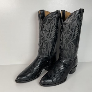 May include: A pair of black cowboy boots. The boots have a textured pattern on the lower part and decorative stitching on the upper shaft. The boots have pointed toes and small heels.