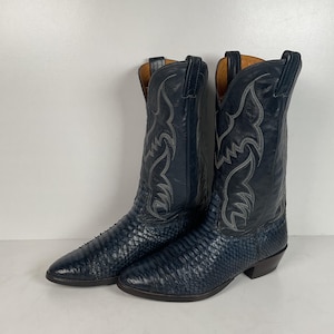 May include: A pair of navy blue cowboy boots. The boots have a textured, snake-like pattern on the lower part and decorative stitching on the upper shaft. The heels are dark brown.