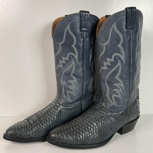 May include: A pair of dark blue cowboy boots with a snakeskin pattern. The boots have a pointed toe and a high heel.