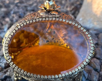 3-sided Ormolu beveled oval amber colored glass jewelry casket with intricate gilded filigree, rose top, three footed.