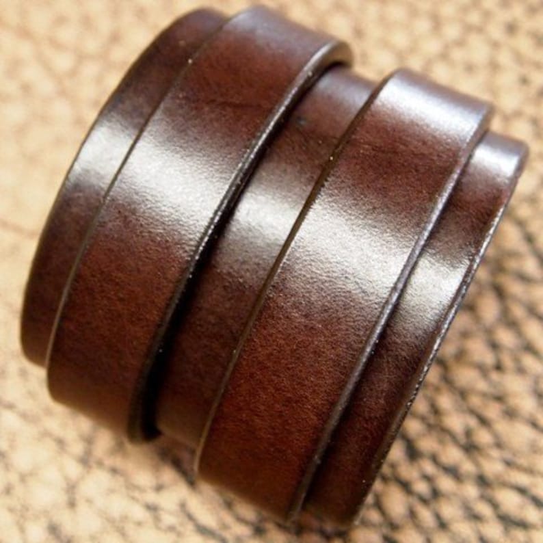 May include: A brown leather bracelet with multiple layers of leather. The bracelet is made of a thick, durable leather and has a simple, elegant design.