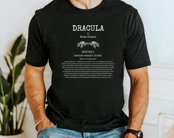 Könnte beinhalten: Schwarzes T-Shirt mit dem Titel "DRACULA" von Bram Stoker und Text aus Jonathan Harkers Journal. Das Design beinhaltet eine Fledermaus-Illustration. Ein literaturthematisches Kleidungsstück, ideal für Fans klassischer Literatur.