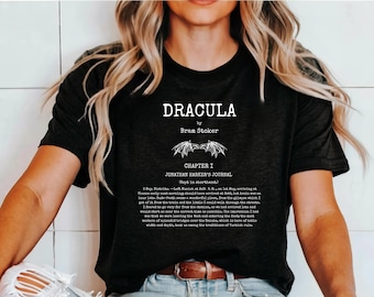 Könnte beinhalten: Schwarzes T-Shirt mit dem Titel "DRACULA" von Bram Stoker und Text aus Jonathan Harkers Journal. Das Design ist weiß, mit einer Vintage-Ästhetik. Das T-Shirt wird von einer Person getragen.