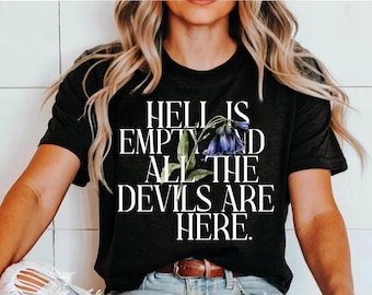 May include: Black t-shirt with white text that reads "Hell is empty and all the devils are here."  A floral design with purple flowers is behind the text.