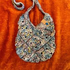 Multicolor floral design granny square bag with buttons and cork ribbon detail.