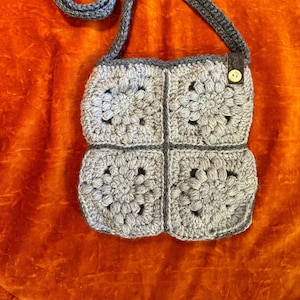 Grey floral design granny square crochet bag with buttons and cork ribbon detail.