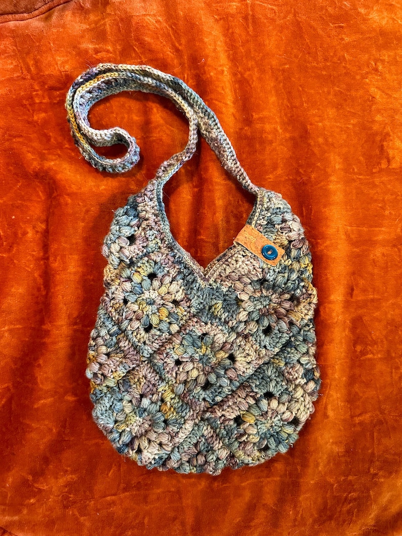 Multicolor floral design granny square bag with buttons and cork ribbon detail.