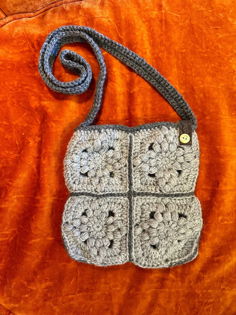 Grey floral design granny square crochet bag with buttons and cork ribbon detail.