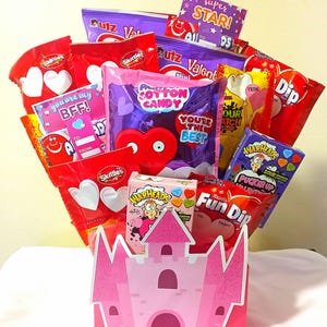 May include: A candy bouquet featuring a pink castle-shaped container filled with various candies and treats. The bouquet includes Skittles, Fun Dip, Warheads, and other Valentine's Day-themed sweets. The bouquet is decorated with heart-shaped accents and cards.