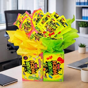 May include: A candy bouquet featuring Sour Patch Kids boxes and individual packs. The boxes are green and yellow, with watermelon and original flavors. The arrangement includes yellow and green tissue paper, creating a colorful and playful gift.