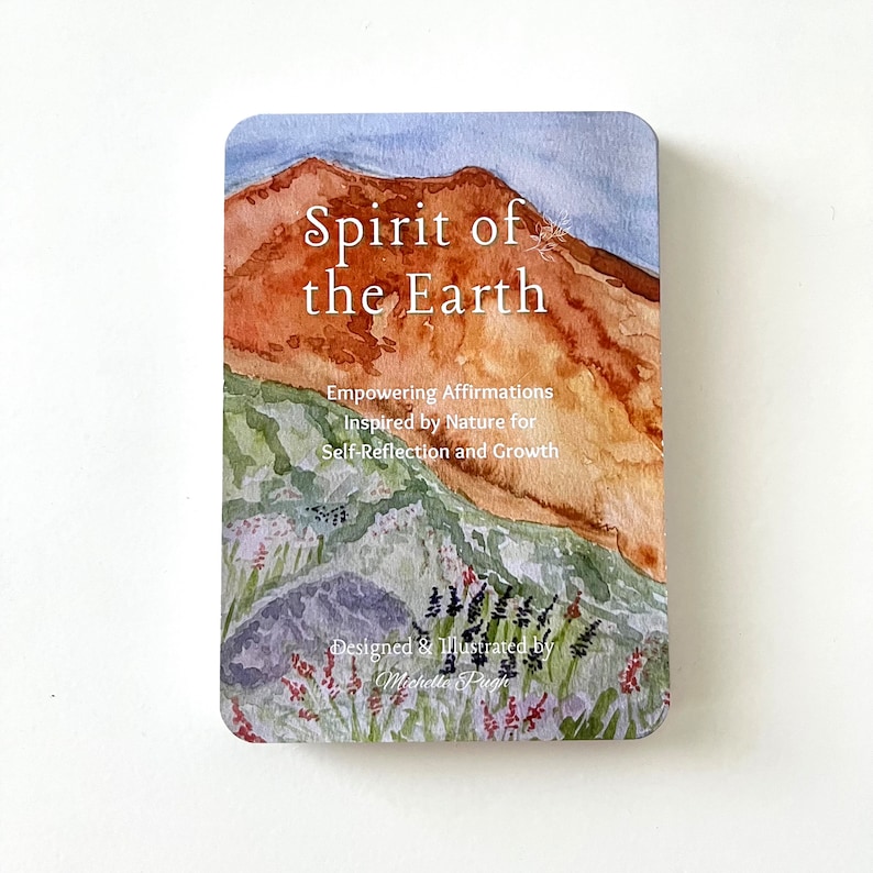 May include: A card with a watercolor illustration of a mountain range with a blue sky. The text "Spirit of the Earth" is written in white on the card. The text "Empowering Affirmations Inspired by Nature for Self-Reflection and Growth" is written in black below the title. The text "Designed & Illustrated by Michelle Pugh" is written in black at the bottom of the card.