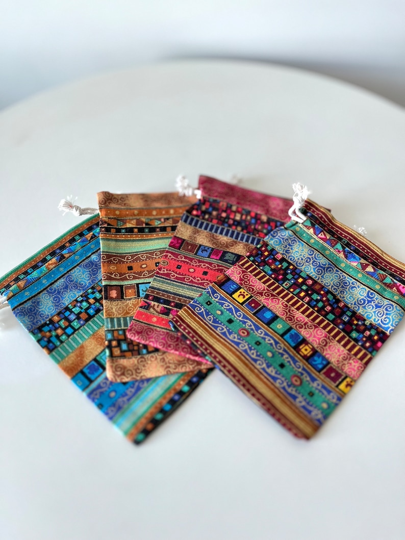 May include: Five small drawstring bags with colorful geometric patterns. The bags are made of fabric and have a variety of colors, including red, blue, green, and gold.
