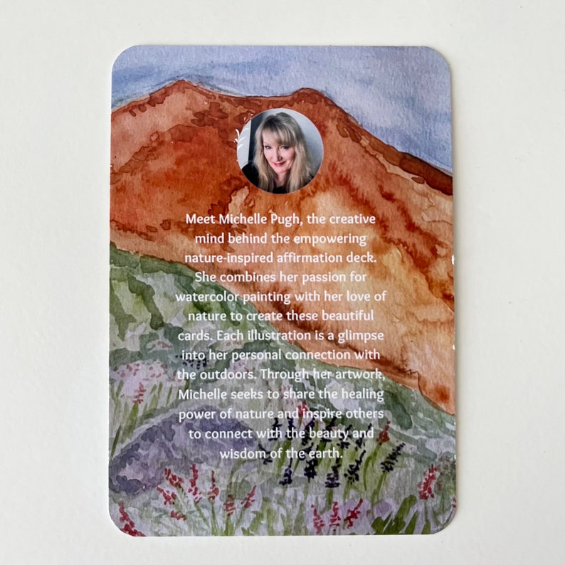 May include: A watercolor illustration of a mountain landscape with a woman's portrait in a circle. The text reads "Meet Michelle Pugh, the creative mind behind the empowering nature-inspired affirmation deck. She combines her passion for watercolor painting with her love of nature to create these beautiful cards. Each illustration is a glimpse into her personal connection with the outdoors. Through her artwork, Michelle seeks to share the healing power of nature and inspire others to connect with the beauty and wisdom of the earth."
