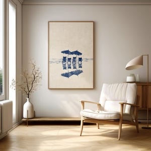 May include: A framed print of a blue and white watercolor illustration of beach chairs and umbrellas reflected in the water.