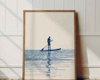 Puede incluir: Una impresión enmarcada de una silueta azul de una persona haciendo paddle surf en una masa de agua con un fondo azul claro.