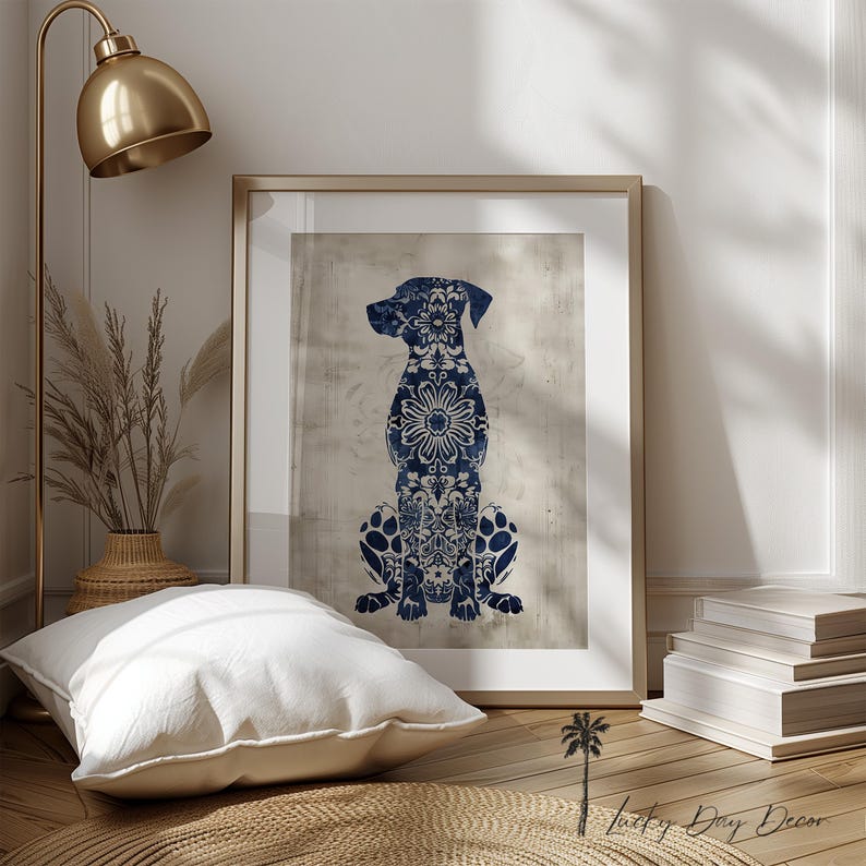 K&ouml;nnte beinhalten: Ein blauer und wei&szlig;er floral gemusterter Hundesilhouetten-Druck in einem goldenen Rahmen. Der Druck ist auf einem strukturierten beigefarbenen Hintergrund. Der Druck h&auml;ngt an einer wei&szlig;en Wand.