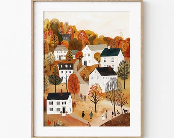 May include: A framed art print showing a village scene in autumn. White houses with black roofs are set amongst trees with orange and yellow leaves. People and a dog are walking on paths. The artwork is in a wooden frame.