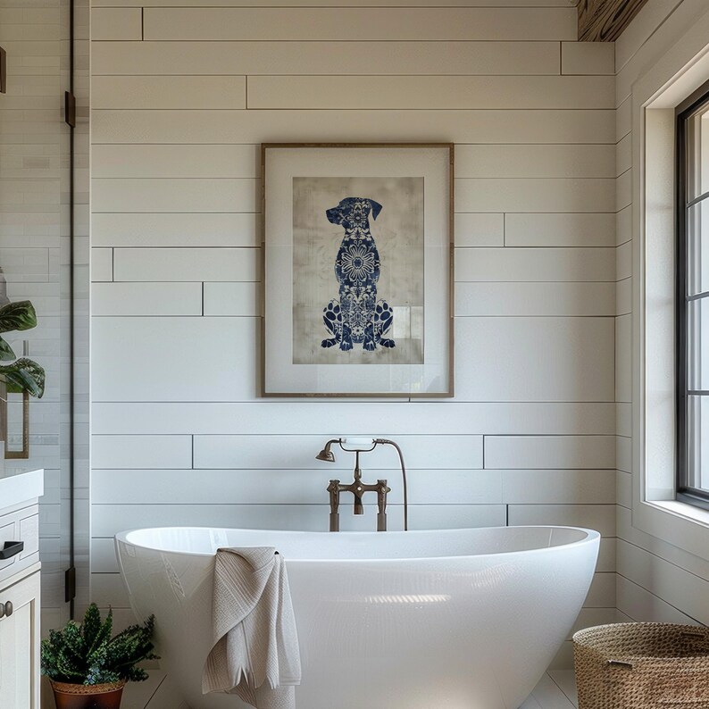 K&ouml;nnte beinhalten: Eine wei&szlig;e freistehende Badewanne mit einem wei&szlig;en Handtuch &uuml;ber dem Rand. Die Badewanne befindet sich in einem Badezimmer mit wei&szlig;en Schiffslappenw&auml;nden und einem gerahmten Druck eines blauen und wei&szlig;en Hundesilhouetten.