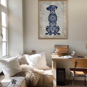 K&ouml;nnte beinhalten: Ein blauer und wei&szlig;er Wandkunstdruck mit einer Hundesilhouette in einem goldenen Rahmen, der an einer wei&szlig;en Wand &uuml;ber einem Holztisch mit B&uuml;chern und einem Stuhl h&auml;ngt.