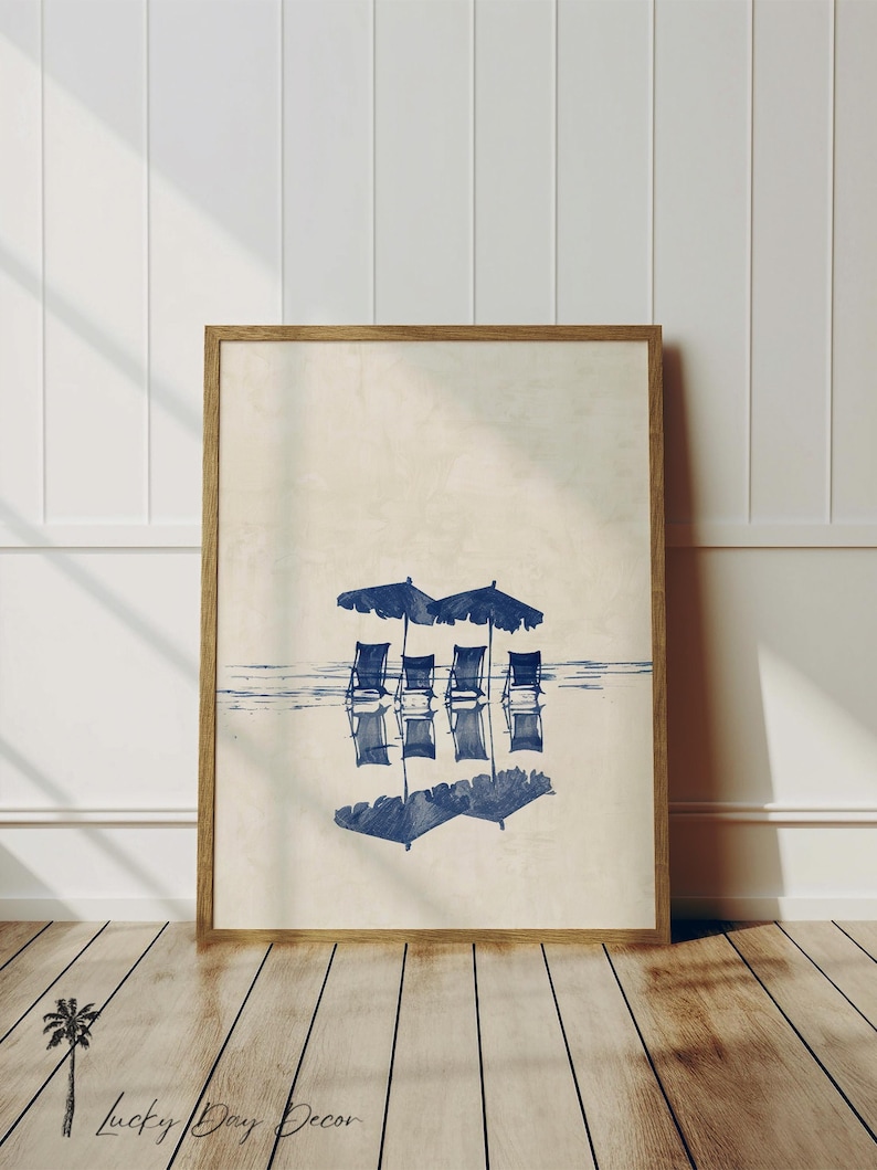 May include: A framed print of a beach scene with four blue chairs under blue umbrellas reflected in the water.