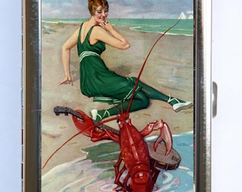 May include: A vintage illustration of a woman in a green swimsuit sitting on a beach with a red lobster holding a banjo.