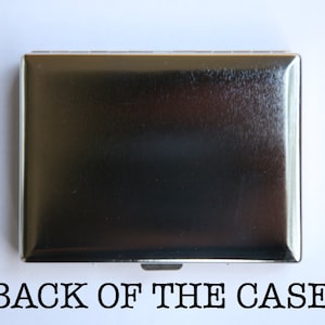 May include: The back of a silver cigarette case. The case is smooth and has a slightly textured surface.