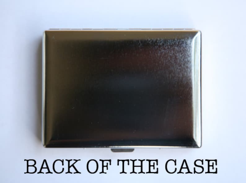 May include: The back of a silver cigarette case. The case is smooth and has a slightly textured surface.